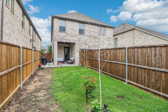 back of property with a patio, a fenced backyard, brick siding, a shingled roof, and a lawn