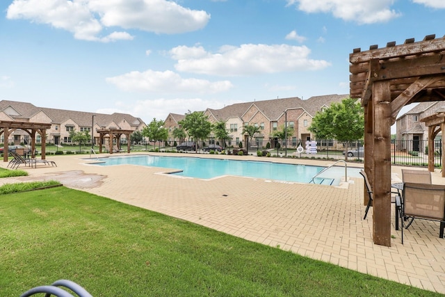 community pool with a patio area, fence, a pergola, and a residential view