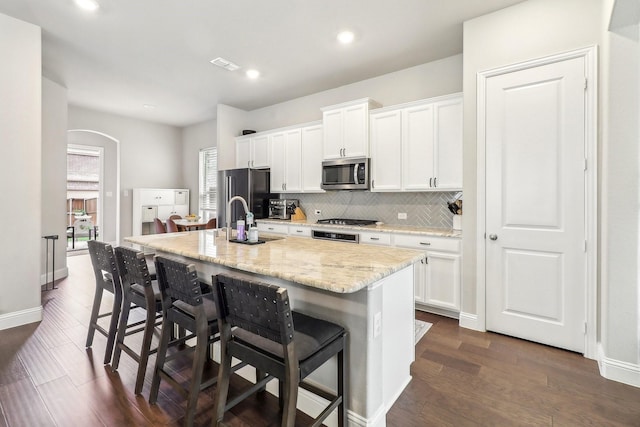 kitchen featuring a sink, appliances with stainless steel finishes, white cabinets, and arched walkways