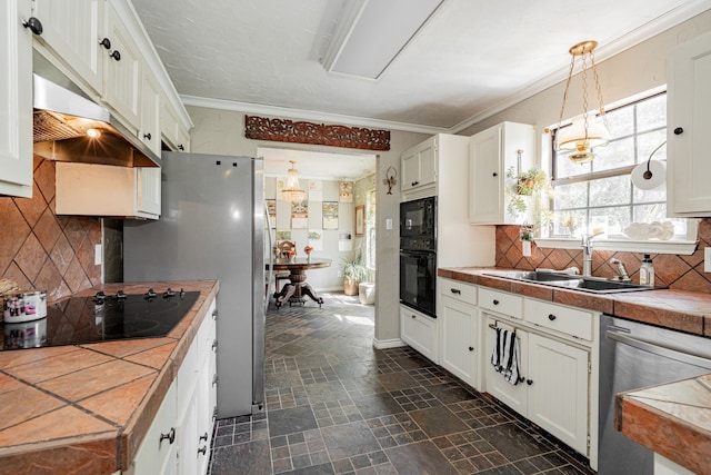 kitchen with tile counters, stone finish flooring, a sink, and black appliances