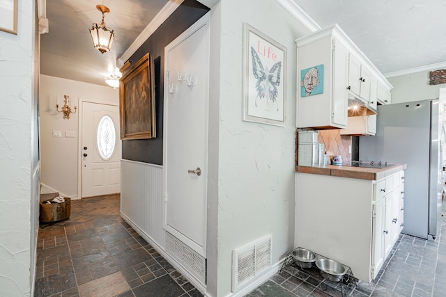 entryway featuring ornamental molding, stone finish flooring, and visible vents