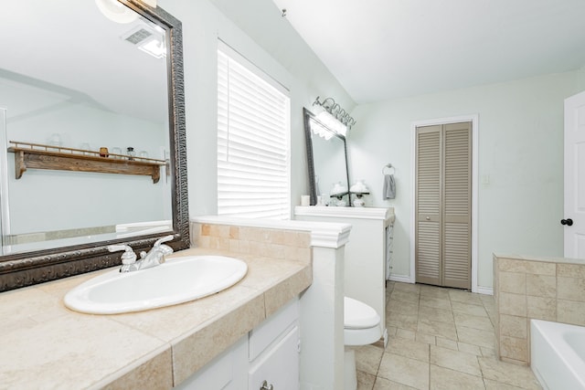 bathroom featuring a garden tub, a closet, toilet, and vanity
