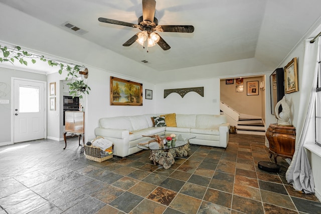 living area featuring ceiling fan, visible vents, stairway, baseboards, and stone tile flooring