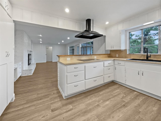 kitchen with light countertops, extractor fan, a sink, and light wood-type flooring