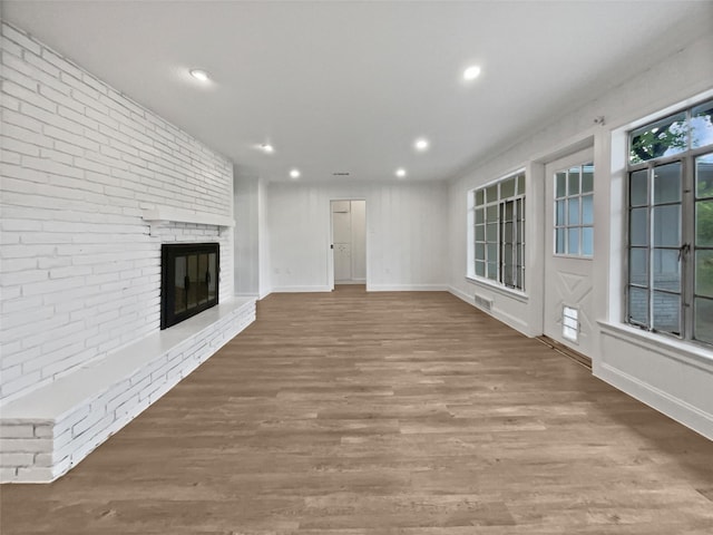 unfurnished living room featuring a brick fireplace, recessed lighting, wood finished floors, and visible vents