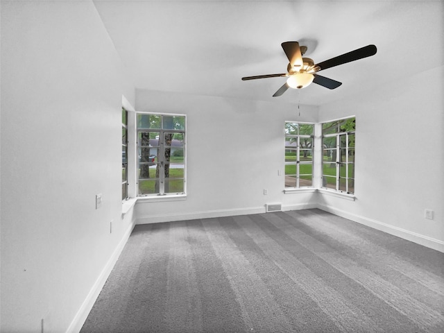 carpeted empty room with baseboards, ceiling fan, and visible vents