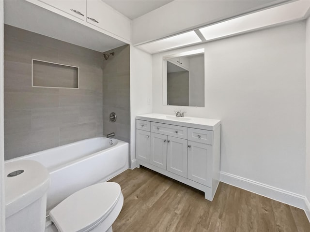 bathroom featuring vanity, toilet, baseboards, wood finished floors, and  shower combination