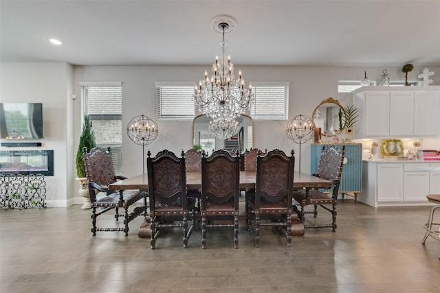 dining area with an inviting chandelier, recessed lighting, a glass covered fireplace, and wood finished floors