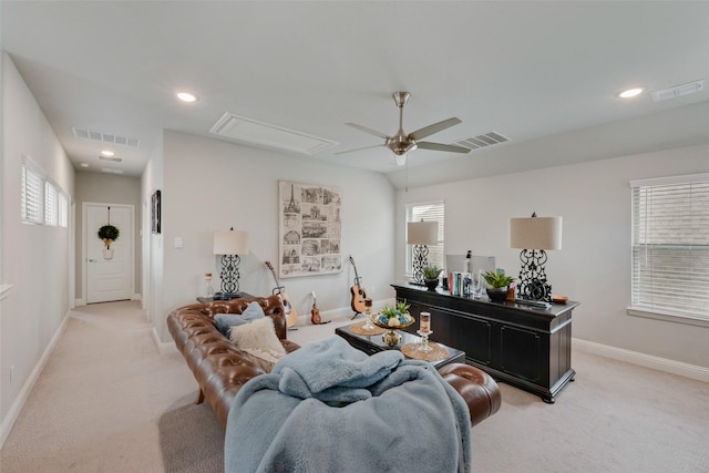 living area featuring ceiling fan, attic access, light colored carpet, and visible vents