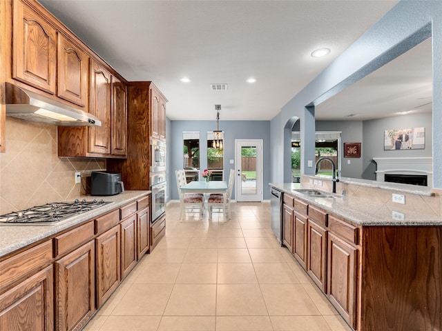5732 Chateau Dr, Sachse, TX 75048 - kitchen featuring a sink, stainless steel appliances, under cabinet range hood, tasteful backsplash, and arched walkways