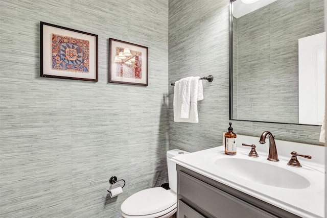 half bath with toilet, tile walls, and vanity