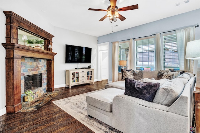 living room with a ceiling fan, visible vents, a brick fireplace, wood finished floors, and baseboards