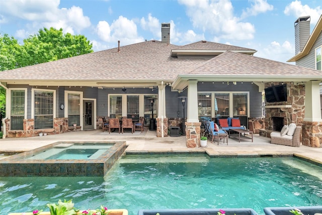 back of property with a patio, stone siding, a shingled roof, and an outdoor living space with a fireplace