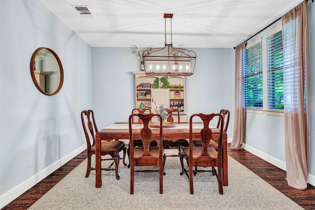 dining space with baseboards, a notable chandelier, wood finished floors, and visible vents