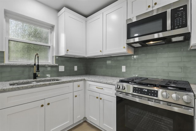 2708 Ash Park Dr, Richland Hills, TX 76118 - kitchen featuring stainless steel appliances, a sink, white cabinetry, tasteful backsplash, and light stone counters