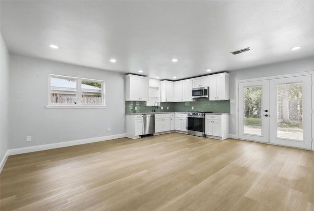 2708 Ash Park Dr, Richland Hills, TX 76118 - kitchen with stainless steel appliances, baseboards, light wood-style floors, white cabinetry, and tasteful backsplash