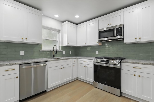 2708 Ash Park Dr, Richland Hills, TX 76118 - kitchen featuring stainless steel appliances, a sink, light wood-type flooring, white cabinetry, and backsplash