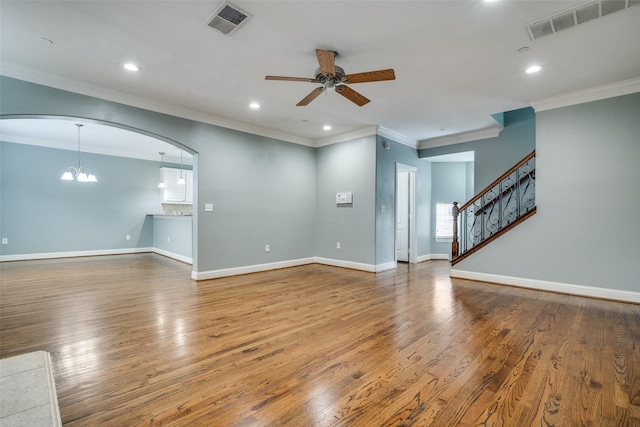 unfurnished living room featuring arched walkways, ceiling fan with notable chandelier, wood finished floors, and visible vents