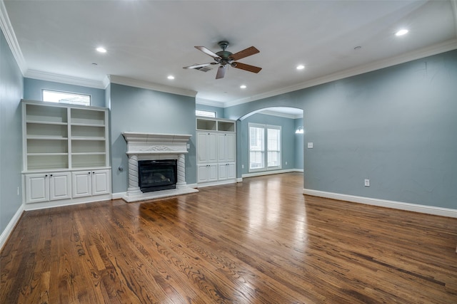 unfurnished living room with visible vents, a glass covered fireplace, wood finished floors, ceiling fan, and arched walkways