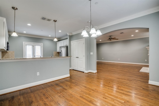 kitchen featuring stainless steel refrigerator with ice dispenser, visible vents, light stone countertops, ceiling fan with notable chandelier, and white cabinetry