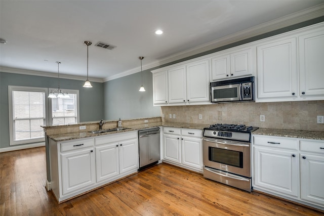kitchen featuring visible vents, appliances with stainless steel finishes, a sink, a peninsula, and light wood-style floors