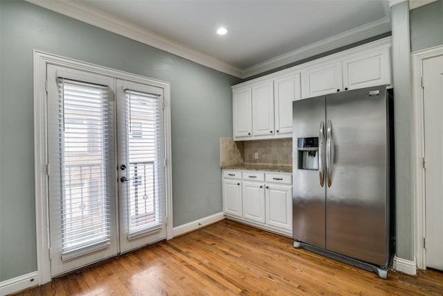 kitchen featuring tasteful backsplash, baseboards, stainless steel fridge, ornamental molding, and white cabinetry