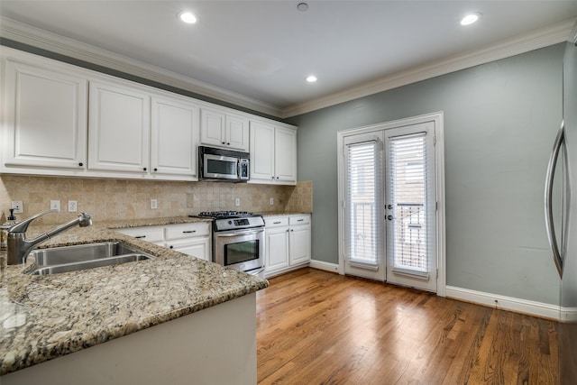 kitchen with decorative backsplash, baseboards, french doors, a sink, and appliances with stainless steel finishes