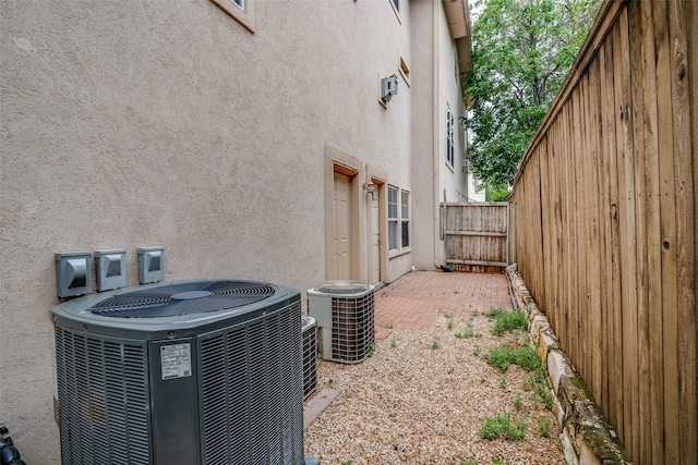 view of property exterior with stucco siding, central air condition unit, and fence