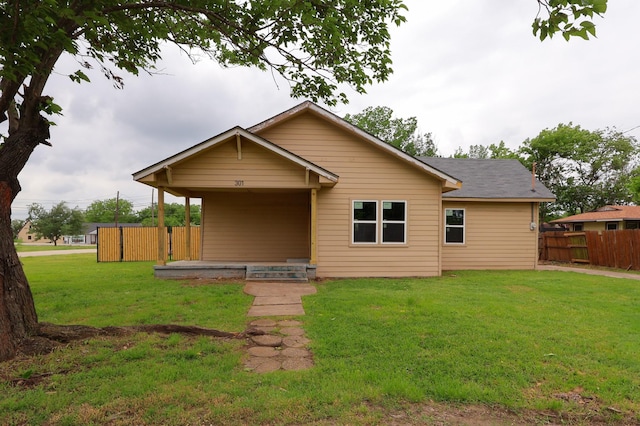 back of property featuring fence and a yard
