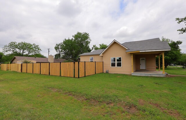 rear view of house featuring a yard and fence