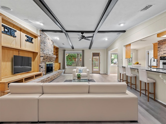 2345 Ravenwood Dr, Grand Prairie, TX 75050 - living area with visible vents, a fireplace, ceiling fan, light wood-type flooring, and vaulted ceiling with beams