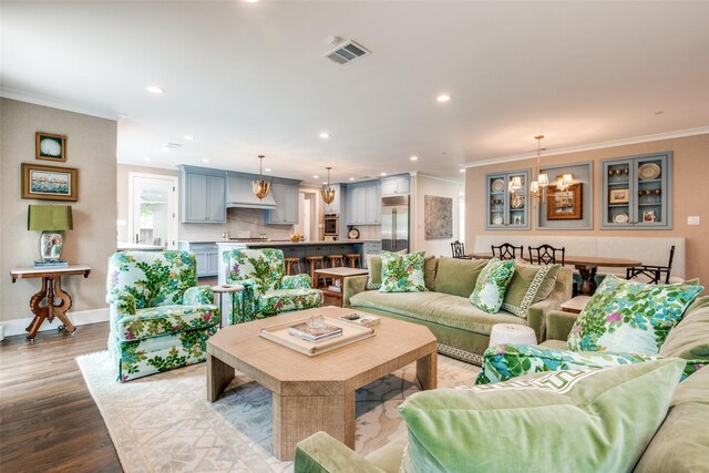 living room with crown molding, an inviting chandelier, dark wood-type flooring, and visible vents