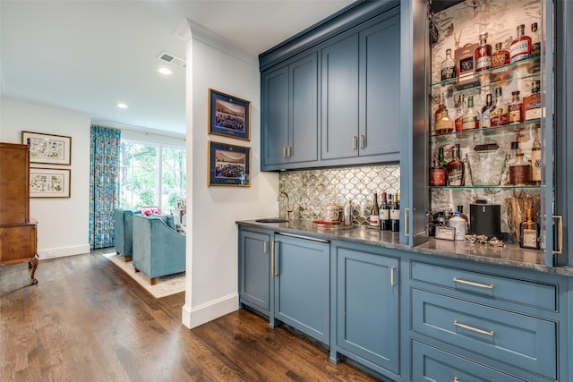 bar with tasteful backsplash, a sink, baseboards, wet bar, and dark wood-type flooring