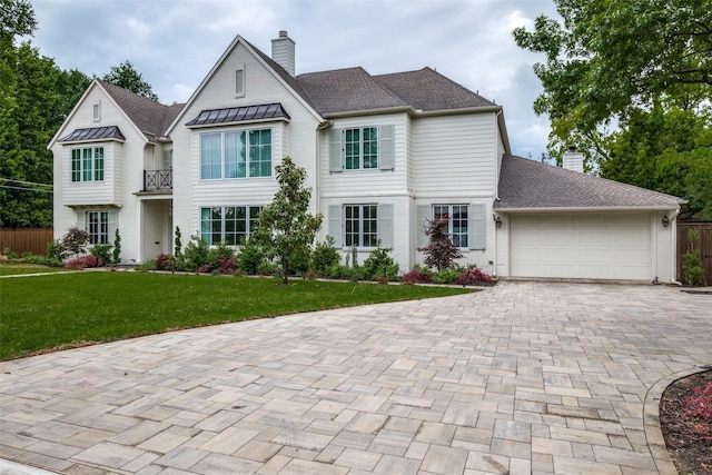 view of front of house featuring an attached garage, decorative driveway, a front yard, and a chimney