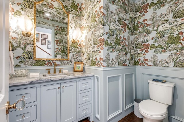 bathroom with a decorative wall, a wainscoted wall, and wallpapered walls