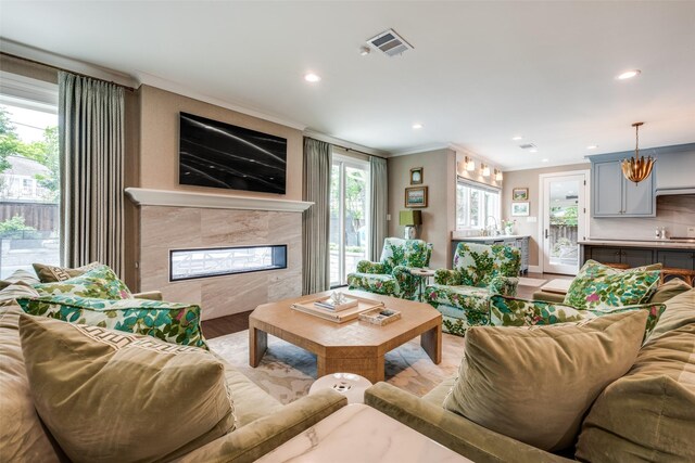 living area with recessed lighting, visible vents, ornamental molding, and a tile fireplace