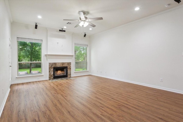 unfurnished living room featuring a ceiling fan, baseboards, a healthy amount of sunlight, and wood finished floors