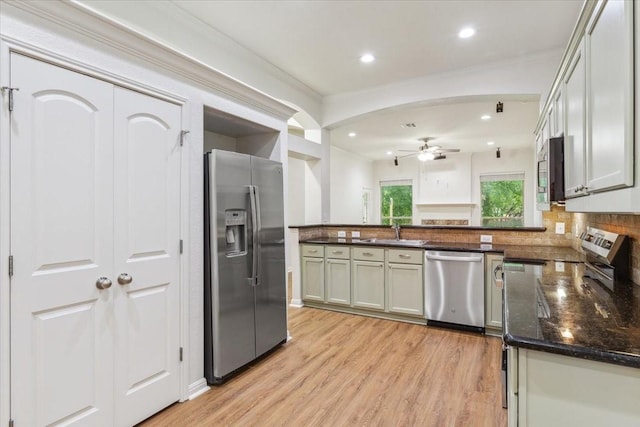 kitchen featuring a sink, stainless steel appliances, a ceiling fan, a peninsula, and light wood-type flooring