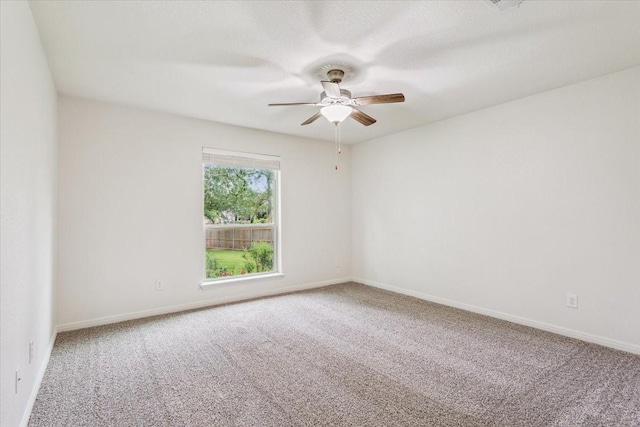carpeted spare room featuring baseboards and ceiling fan