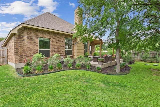 rear view of house featuring a lawn, brick siding, and fence