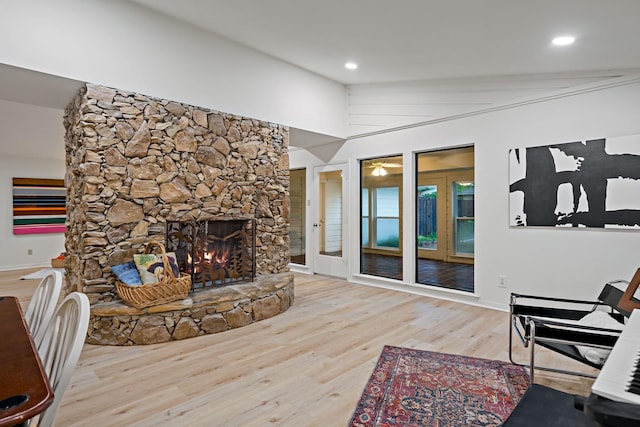 living area with baseboards, a stone fireplace, recessed lighting, and wood finished floors