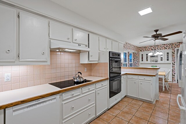 1308 Chesterton Dr, Richardson, TX 75080 - kitchen featuring black appliances, under cabinet range hood, a peninsula, light tile patterned floors, and white cabinetry