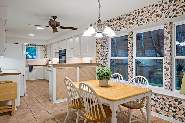 dining room featuring ceiling fan with notable chandelier and light tile patterned flooring