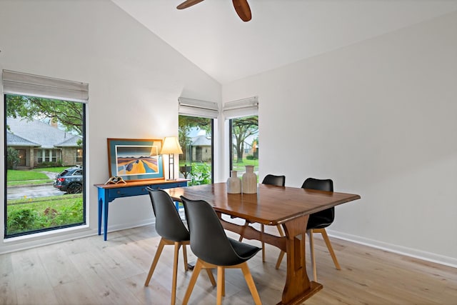 dining room with high vaulted ceiling, plenty of natural light, baseboards, and light wood-type flooring