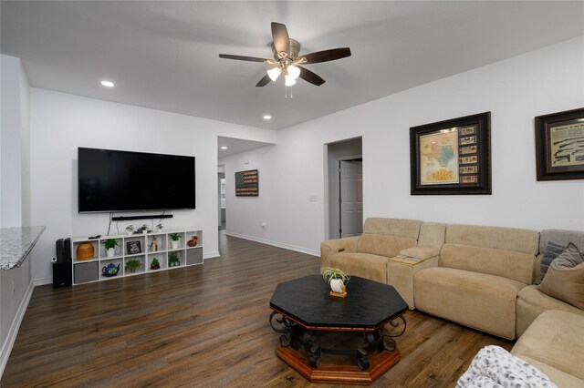 living area with baseboards, ceiling fan, and dark wood finished floors