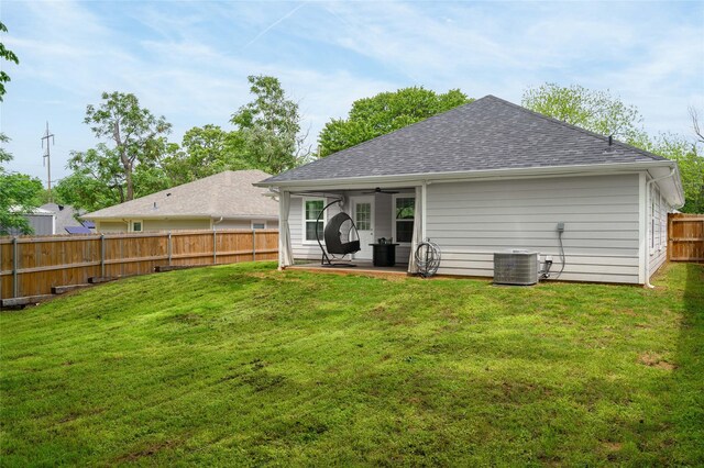 back of property featuring ceiling fan, a fenced backyard, roof with shingles, a patio area, and a yard
