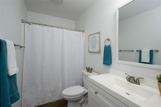 bathroom with vanity, a shower with curtain, toilet, and wood finished floors