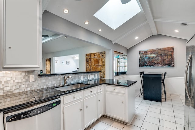 kitchen with white cabinets, a sink, stainless steel appliances, light tile patterned floors, and lofted ceiling with skylight