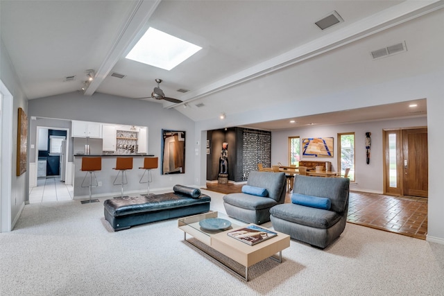 living area featuring visible vents, baseboards, lofted ceiling with skylight, and light carpet