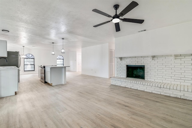 6401 Gate Ridge Cir, Garland, TX 75043 - unfurnished living room featuring a ceiling fan, a textured ceiling, visible vents, a sink, and light wood-style flooring